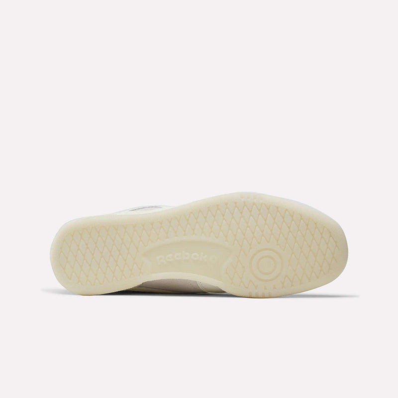 The image displays the bottom view of the Reebok x IDEA Club C 85 Shoes in beige, featuring a textured rubber sole and central Reebok branding that highlights the signature style of Reebok footwear.