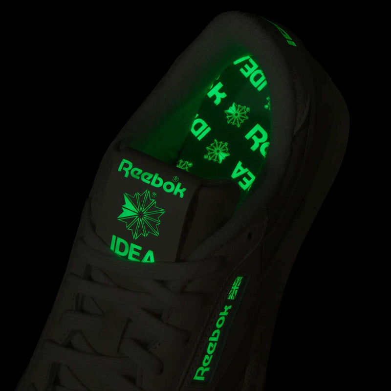 A close-up of the Reebok x IDEA Club C 85 Shoes in black highlights glowing bright green Reebok logos and the word “IDEA”—inspired by the creative vibe of IDEA bookstore—on both the tongue and inner sole.