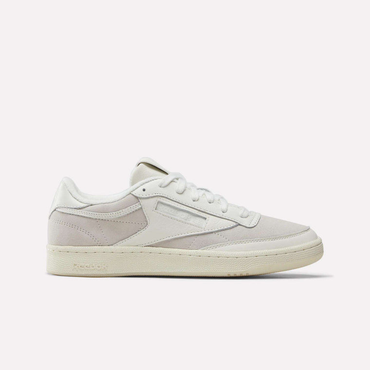 Here is a rewritten version of the sentence, incorporating your provided product data: A side profile of the Reebok x IDEA Club C 85 Shoes in an all-white colorway showcases their premium suede and leather upper, crisp white laces, the signature Reebok logo on the side panel, and a textured rubber sole. Exuding timeless style at every step, these classic Reebok sneakers stand out against a plain light grey background.