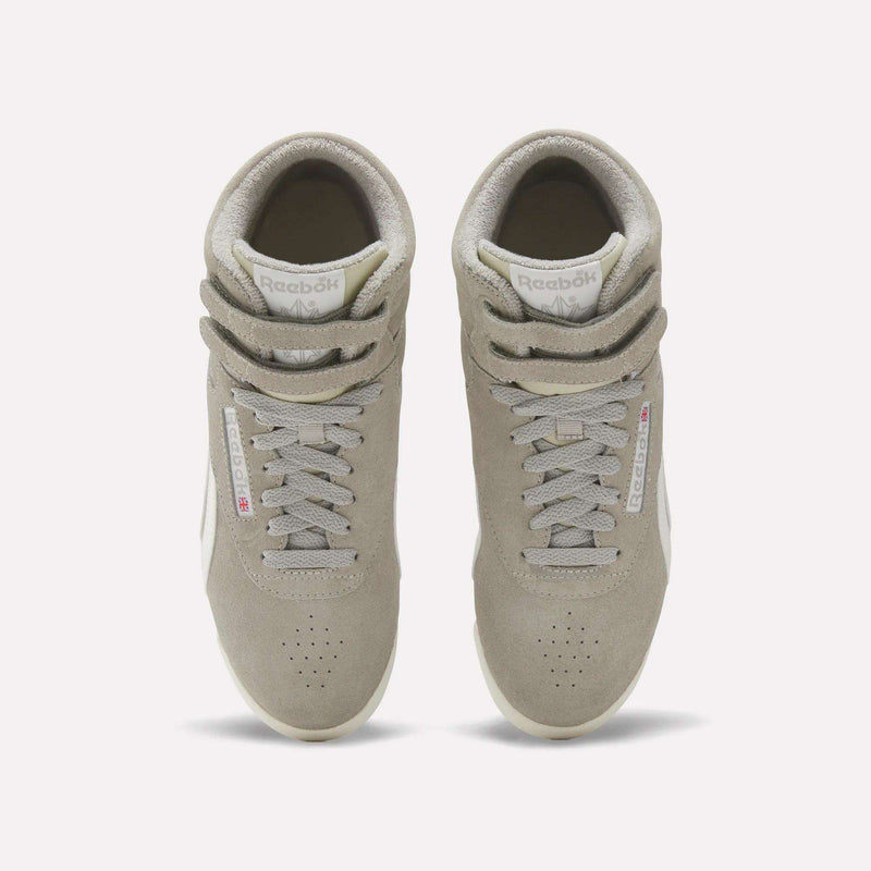A pair of light beige Reebok Women's F/S Hi Shoes seen from above, featuring laces, double straps, perforated toe boxes, a suede upper, and visible Reebok logo tags on the sides.