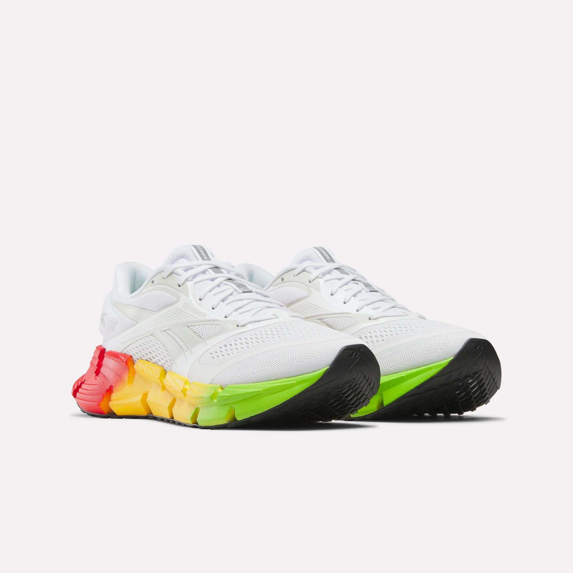 The Reebok Men's FloatZig 2 SoleMates Running Shoes feature a white upper, gradient soles shifting from red at the heel to yellow and green at the toe, lightweight foam midsoles, and black accents on the front of the soles.