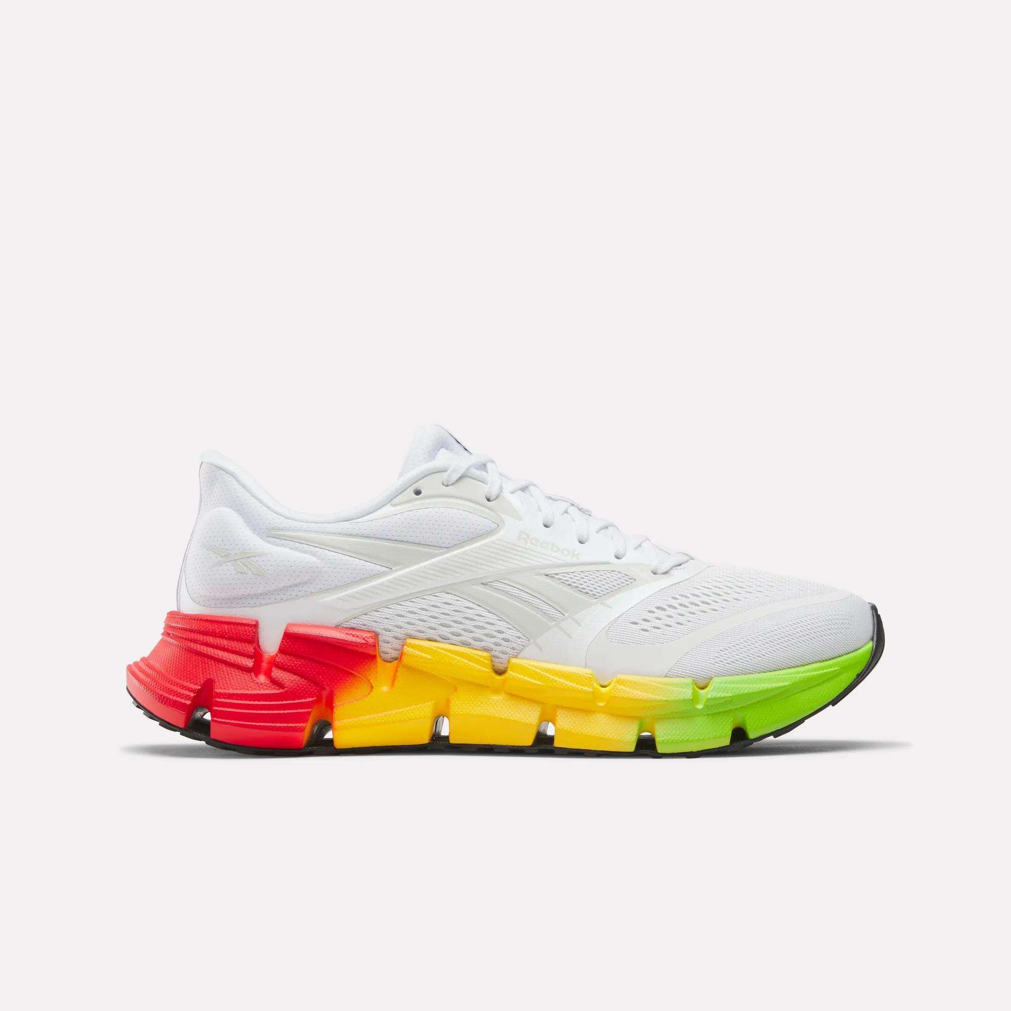 The Reebok Men's FloatZig 2 SoleMates Running Shoes feature a white design, lightweight foam midsole, and a gradient sole fading from red at the heel to orange, yellow, and green at the toe, shown on a plain white background.
