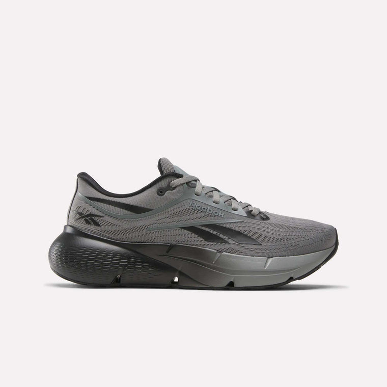 The Reebok Men's Zignition Running Shoe in gray with black accents features a lace-up closure and thick, textured sole, shown in side profile on a plain white background.