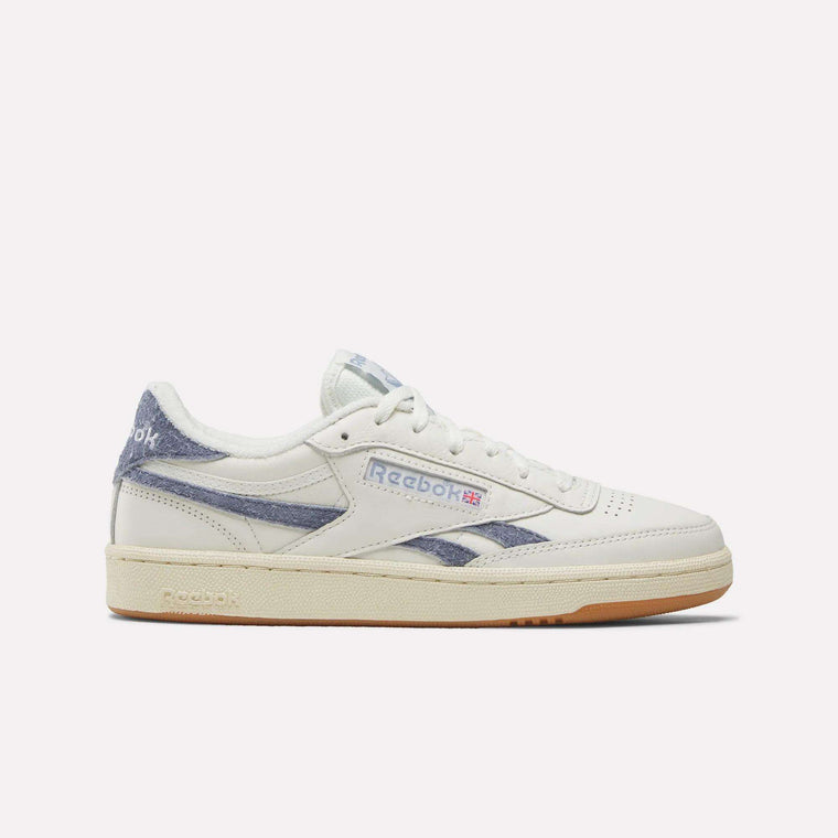 The Reebok Women's Club C Revenge Shoes feature a white design with blue accents, beige sole, and Reebok logos on the side and heel, shown in side profile against a plain white background—ideal for fans of classic women's court shoes.