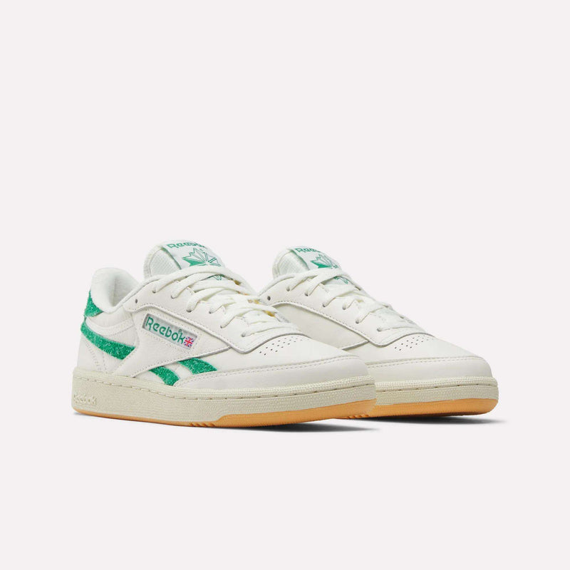 A pair of Reebok Women’s Club C Revenge Shoes in white with green accents and a gum sole, showcased against a plain white background, perfectly capturing the timeless appeal of classic women’s court sneakers.
