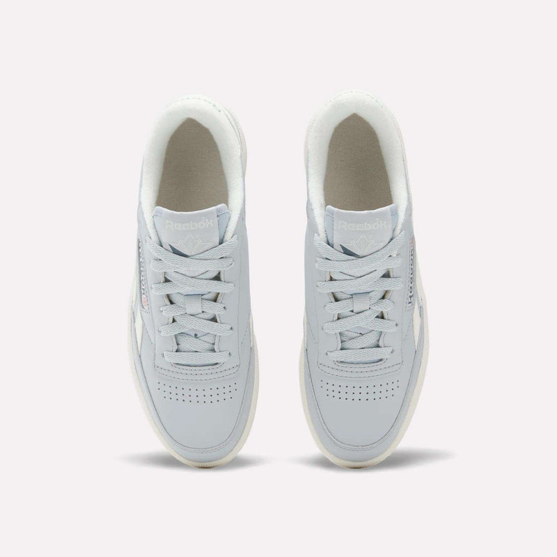 Top view of a pair of Reebok Women's Club C Revenge Shoes in light gray, featuring white soles and laces, placed side by side on a plain background. These casual shoes showcase vintage court style for a timeless look.