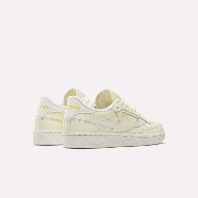 A pair of Women's Club C Revenge Shoes by Reebok in pale yellow with white soles, seen from the side and back against a plain white background. Featuring vintage court-inspired style, these casual shoes for women combine classic design with everyday comfort.