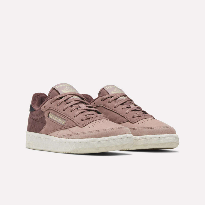A pair of Reebok Women’s Club C 85 Shoes in mauve, featuring cream-colored soles, signature side logo detailing, and a soft nubuck leather texture, displayed against a plain white background.
