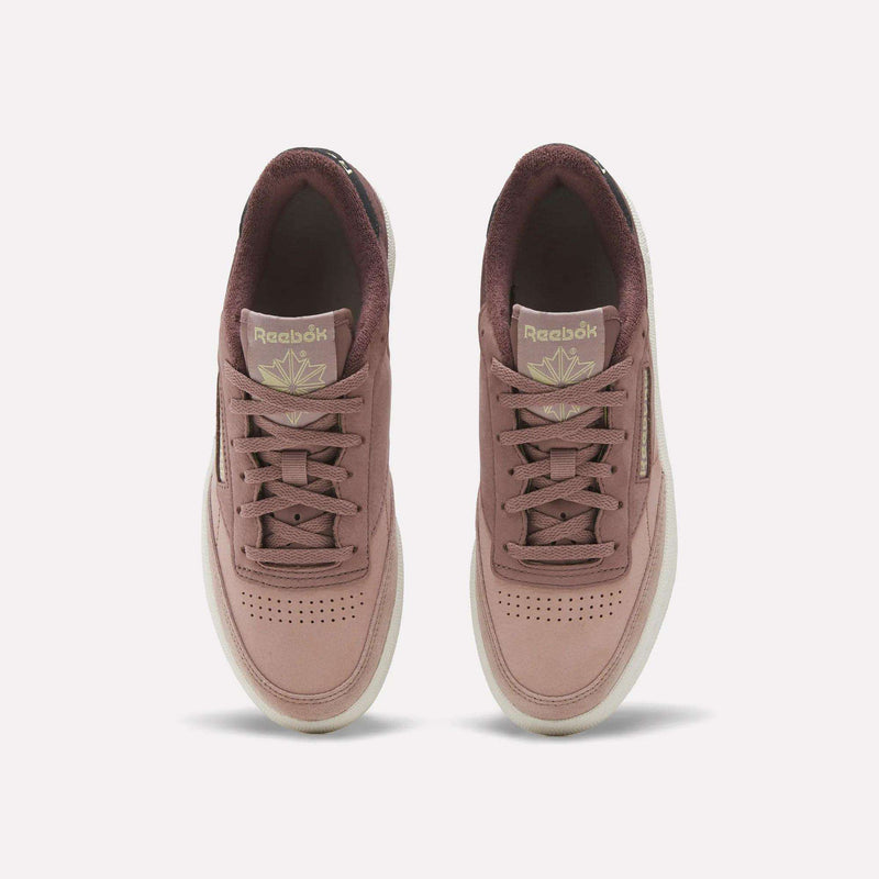 A top-down view of the Reebok Women’s Club C 85 Shoes in mauve highlights their coordinating laces, light soles, and gold Reebok logos on the tongues—these fashionable women’s tennis sneakers boast the premium quality and style of nubuck leather.