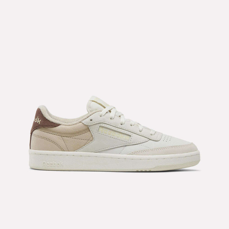 The Women’s Club C 85 Shoes by Reebok are featured in a Linen, Chalk, Elevated Beige, and Vintage Chalk colorway. Crafted from premium nubuck leather with a brown heel accent, these classic women’s tennis sneakers showcase white laces and display the Reebok logo on both the side and heel. The shoes are presented against a plain white background.