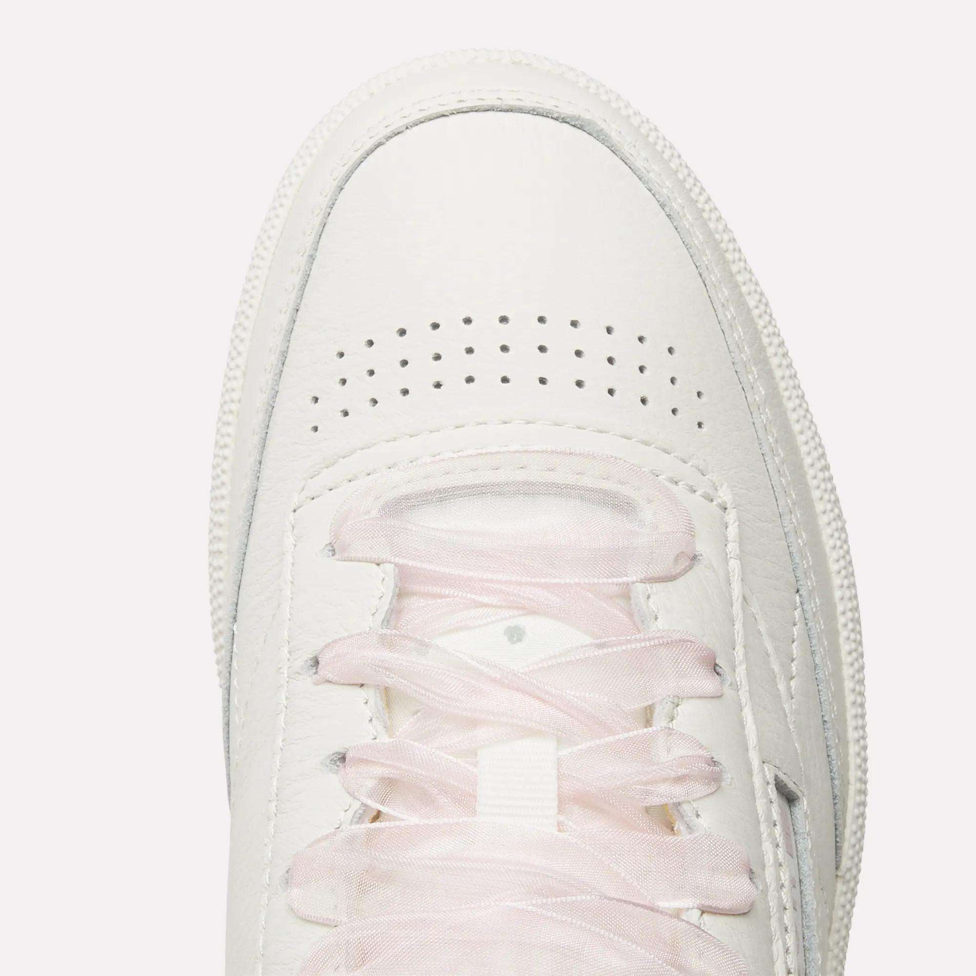 Top view of Women's Club C 85 Vintage Shoes by Reebok in white with light pink laces and toe perforations for ventilation, photographed on a plain white background.