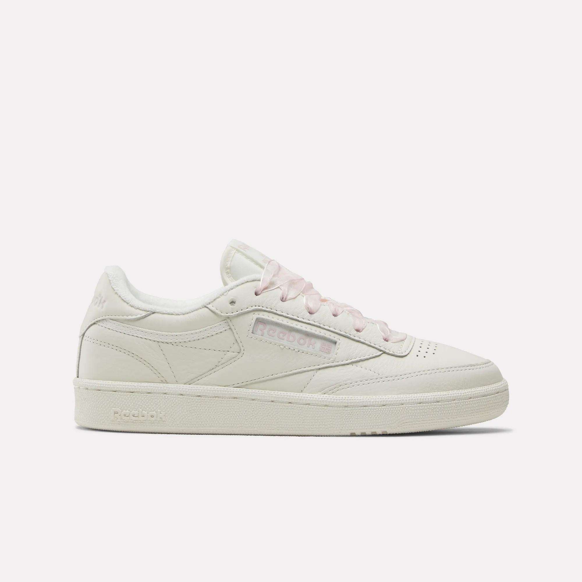 A side view of the Reebok Women's Club C 85 Vintage Shoes in white with light pink laces and accents, featuring classic leather for a subtle retro style, set against a plain white background.