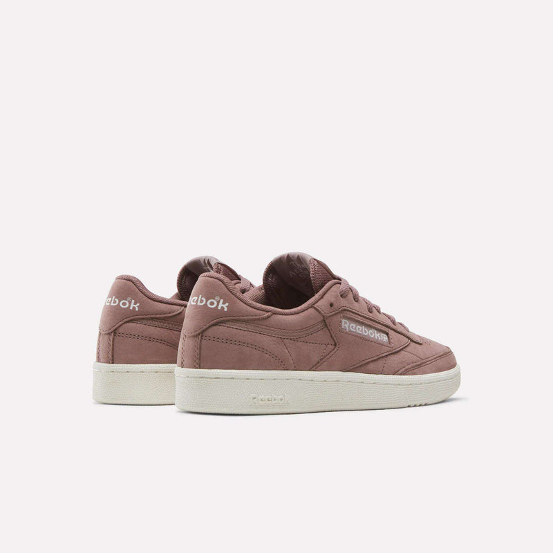 A pair of Reebok Women’s Club C 85 Shoes, featuring a mauve upper and white soles, are displayed side by side on a plain white background to show both the side and back views.