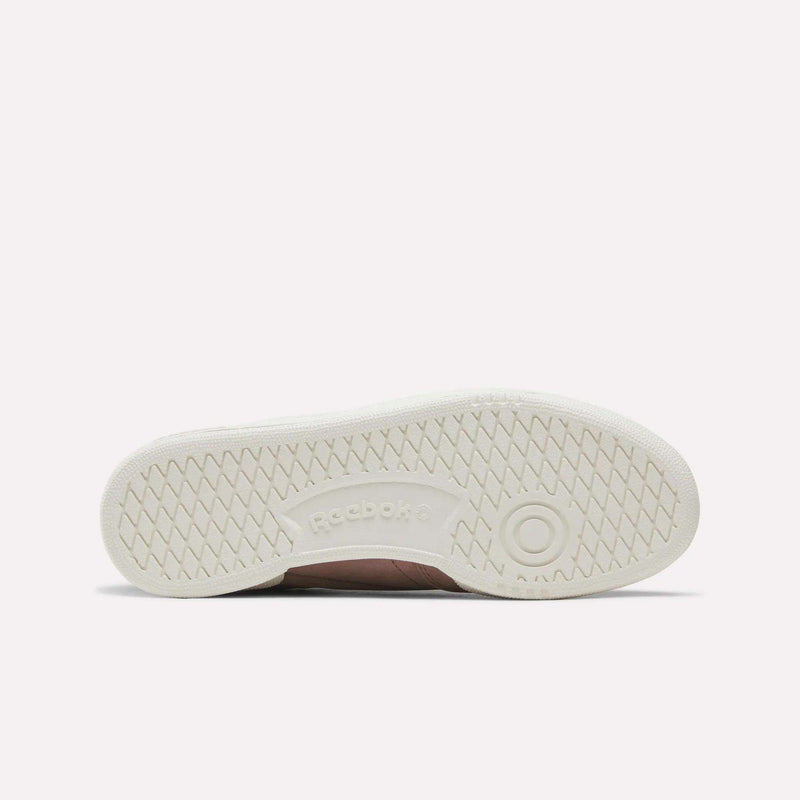 The image displays the sole of the Reebok Women’s Club C 85 Shoes, shown horizontally. The white sole has a textured grip pattern and features the Reebok logo at the center.