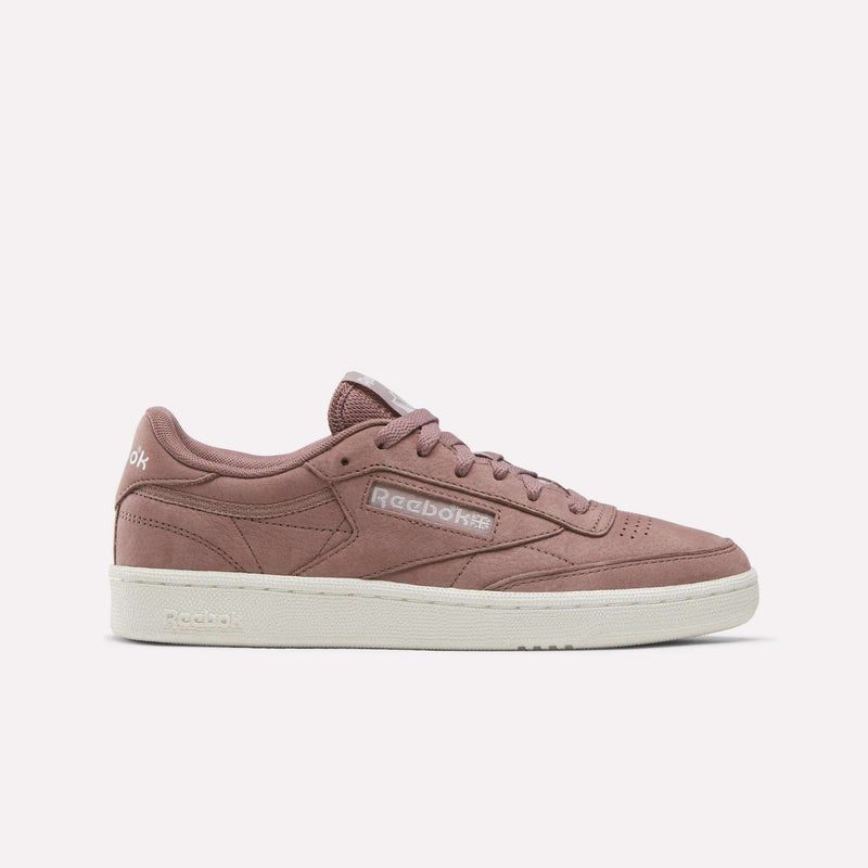 The Reebok Women’s Club C 85 Shoes in Light Cocoa/Chalk feature a mauve pink suede finish with a crisp white sole and classic Reebok branding on the side and tongue. Displayed on a plain white background, these stylish tennis shoes are perfect for women seeking both fashion and comfort.