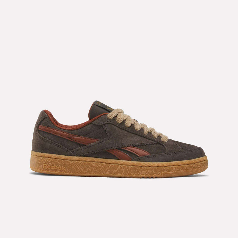 A pair of Reebok Women’s Club C Grounds 70 Shoes in Espresso/Rust/Timber, featuring a gum sole, textured tan laces, and dark brown and reddish-brown accents along the sides. Displayed on a plain white background, these women’s suede sneakers combine retro style with modern comfort.