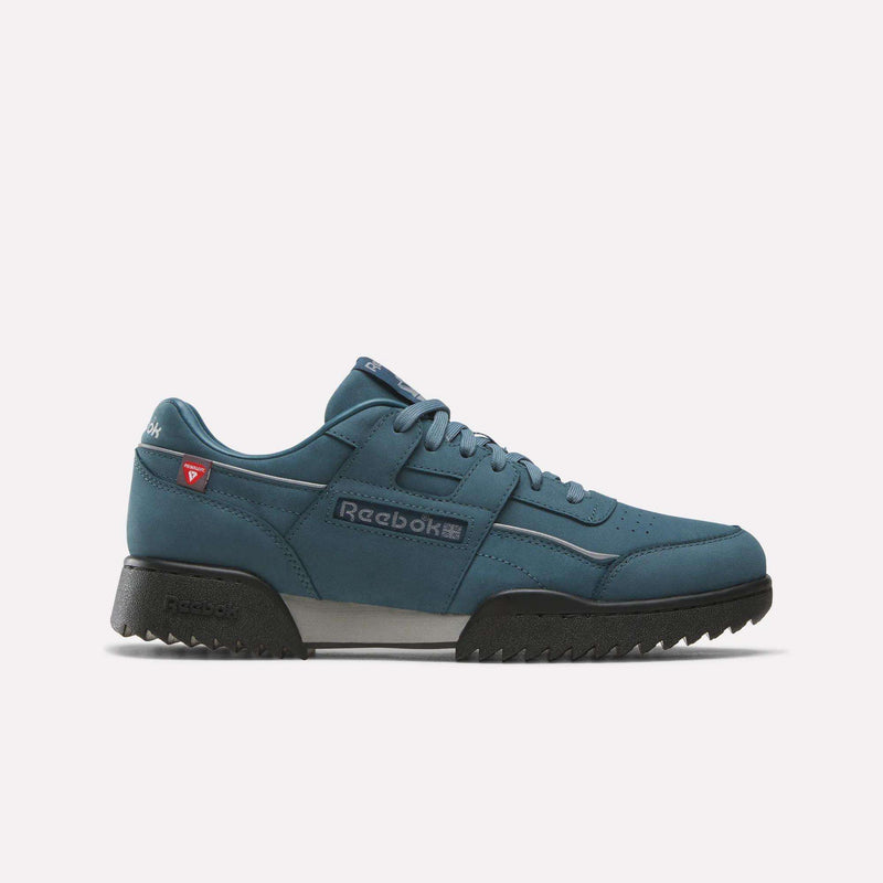 A Reebok Workout Plus Ripple Shoe in Midnight Tide, Black, and Grey 2 is shown from the side on a plain white background. This weather-ready sneaker features a black sole, black laces, and classic Reebok branding on the side. Built with durability in mind, it’s designed to tackle challenging elements with ease.