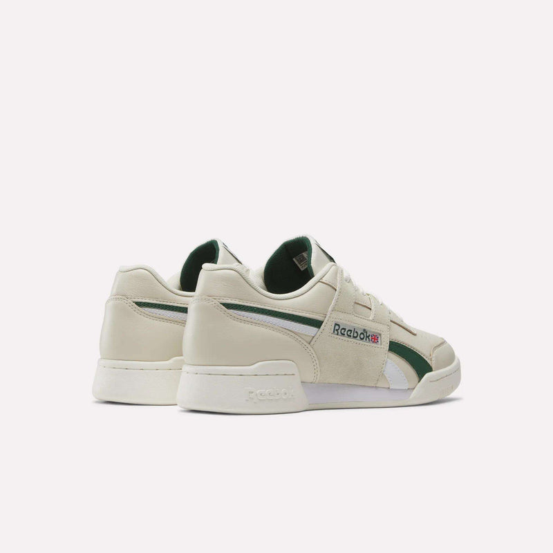 A pair of Reebok Workout Plus Shoes in an off-white colorway with green accents, white midsoles, and the iconic Reebok logo on the side. These classic sneakers are positioned to showcase both their side and back profiles against a simple, plain background.