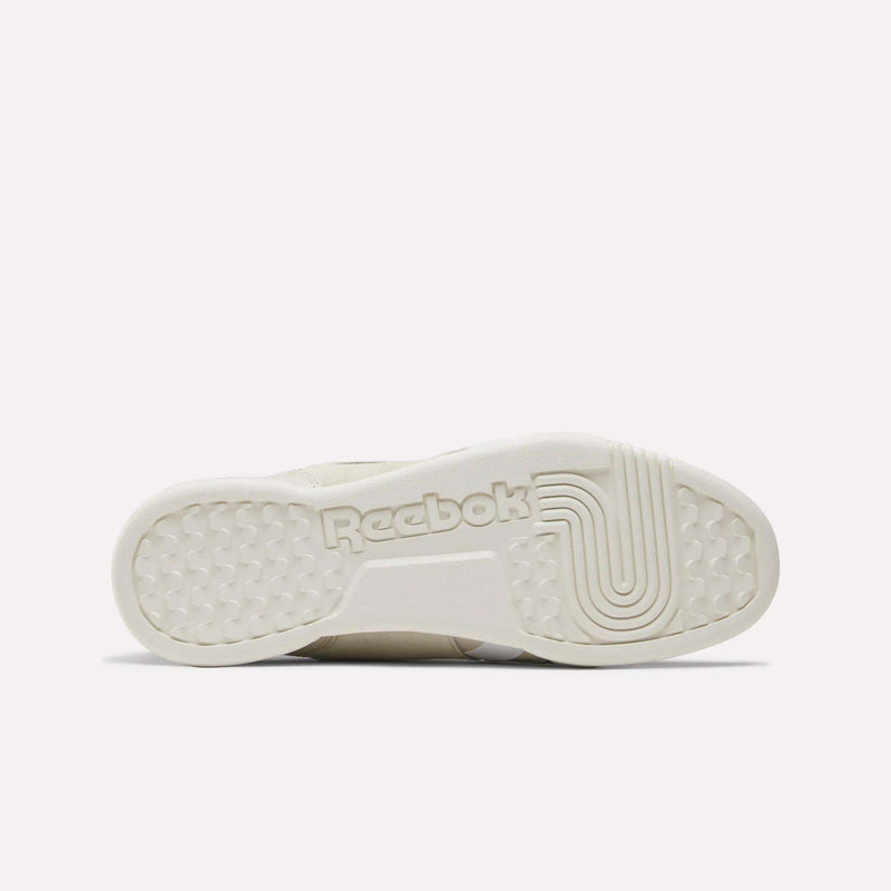 The image displays the outsole of the Reebok Workout Plus Shoes, showcasing the Reebok branding at the center and textured detailing on both the toe and heel sections. The sole features an off-white hue, emphasizing the timeless style characteristic of Reebok leather footwear.