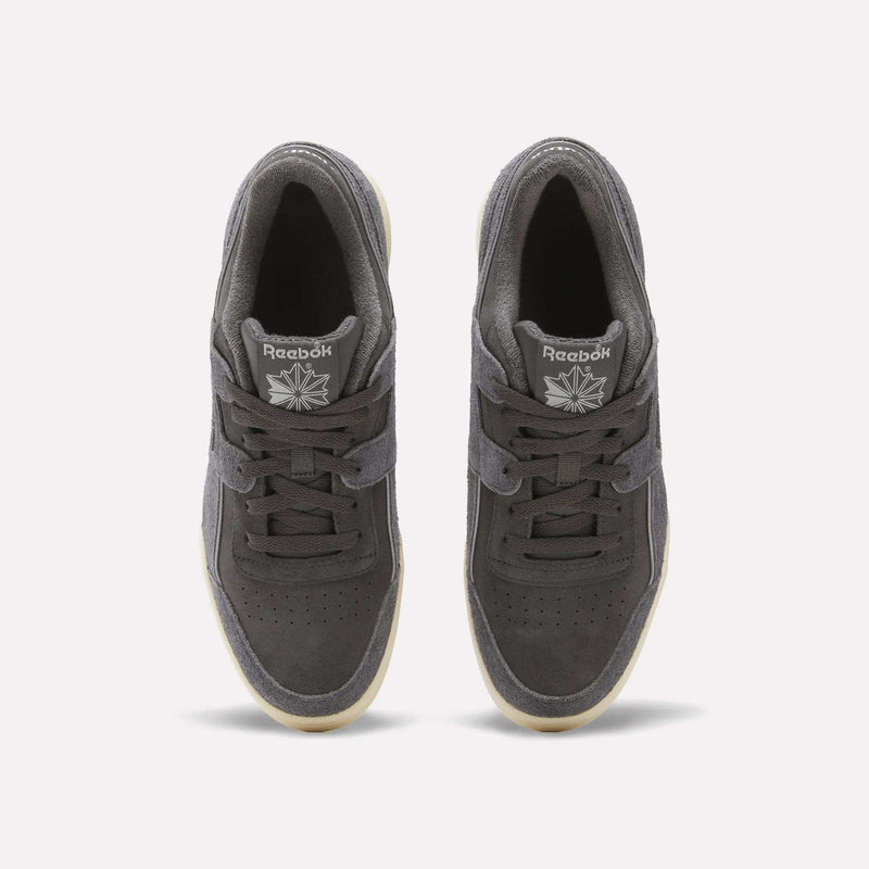 Top view of a pair of dark gray Reebok Workout Plus Shoes featuring laces, white Reebok logos on the tongues, a suede upper, perforated toes, and light outsoles on a plain white background.