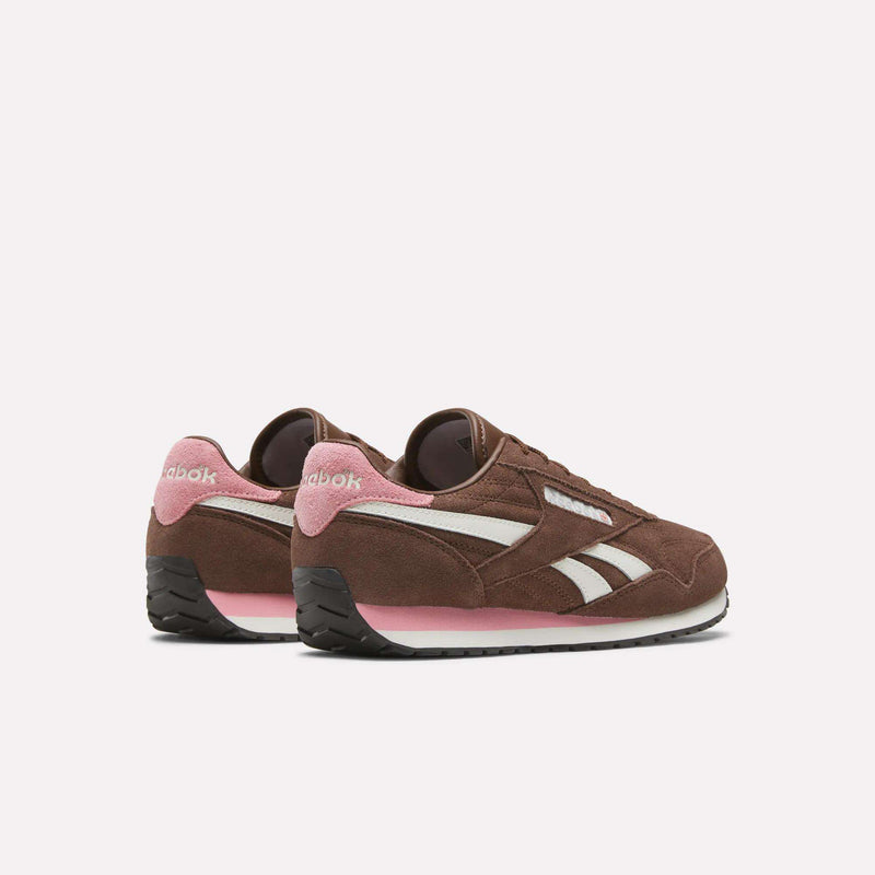 Women’s Classic AZ Shoes by Reebok feature brown suede uppers with white stripes, pink accents on the heel and sole, and black outsoles. Shown angled slightly from the back against a white background, these vintage-inspired sneakers offer timeless style and comfort for women’s running.