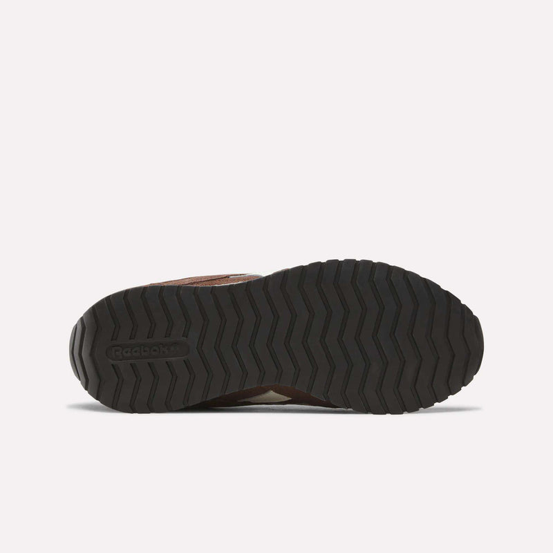 The image displays the bottom view of the Women’s Classic AZ Shoes by Reebok, highlighting a black, textured rubber sole with a zigzag tread pattern. The iconic Reebok logo is embossed on the left side of the sole, underscoring the timeless appeal of these vintage-inspired sneakers.