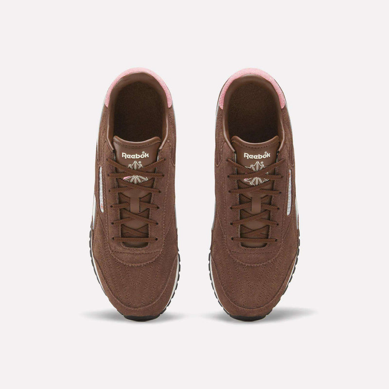 A pair of Women’s Classic AZ Shoes by Reebok in brown with pink accents is shown from above, highlighting the laces, tongue logo, and white side stripes—these vintage sneakers make a stylish addition to any women’s running shoe collection.