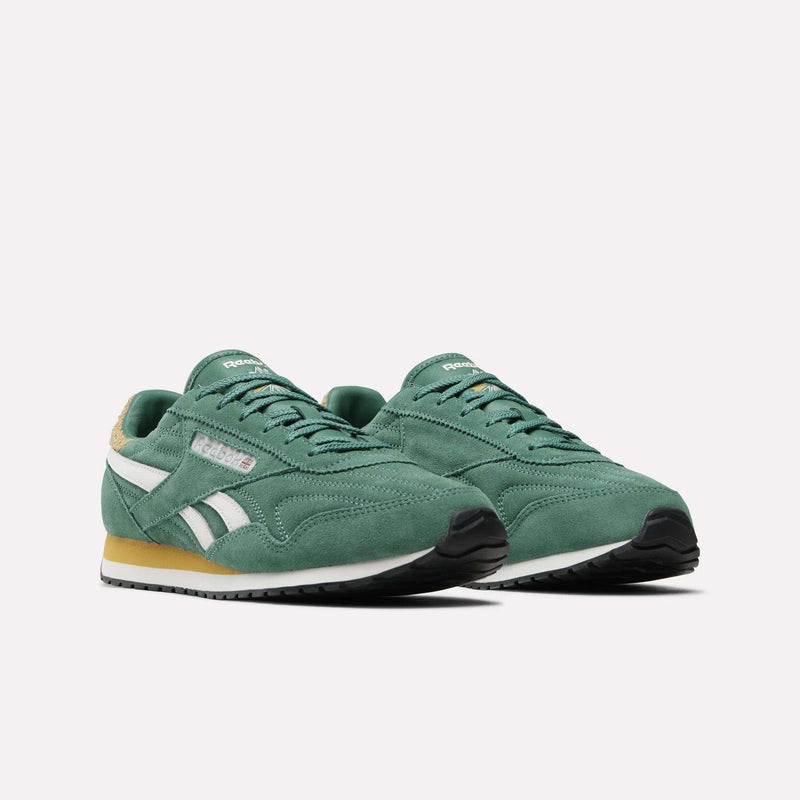 A pair of Women’s Classic AZ Shoes by Reebok, featuring a green upper with white stripes, beige heel detailing, and black rubber soles, are displayed on a white background.