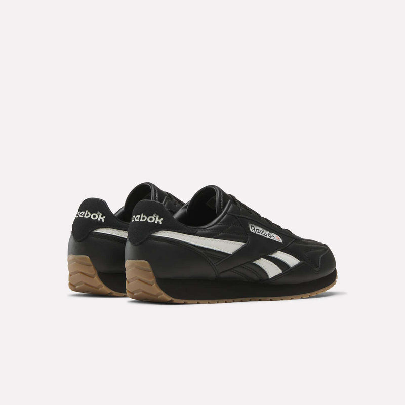 A pair of Reebok Women’s Classic AZ Shoes in black leather with white stripes and gum soles, shown angled to highlight both the sides and backs against a plain white background—ideal for versatile everyday style.