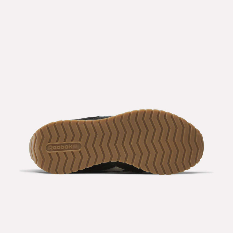 The image displays the bottom view of a women’s Reebok Classic AZ Shoe, featuring a light brown rubber sole with a zigzag pattern. The Reebok logo is embossed on the left side of the sole, and the background is plain white.