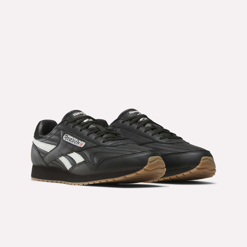 A pair of Women’s Classic AZ Shoes by Reebok in black leather, featuring white side stripes, gum-colored soles, and the Reebok logo on the sides, displayed against a plain white background.