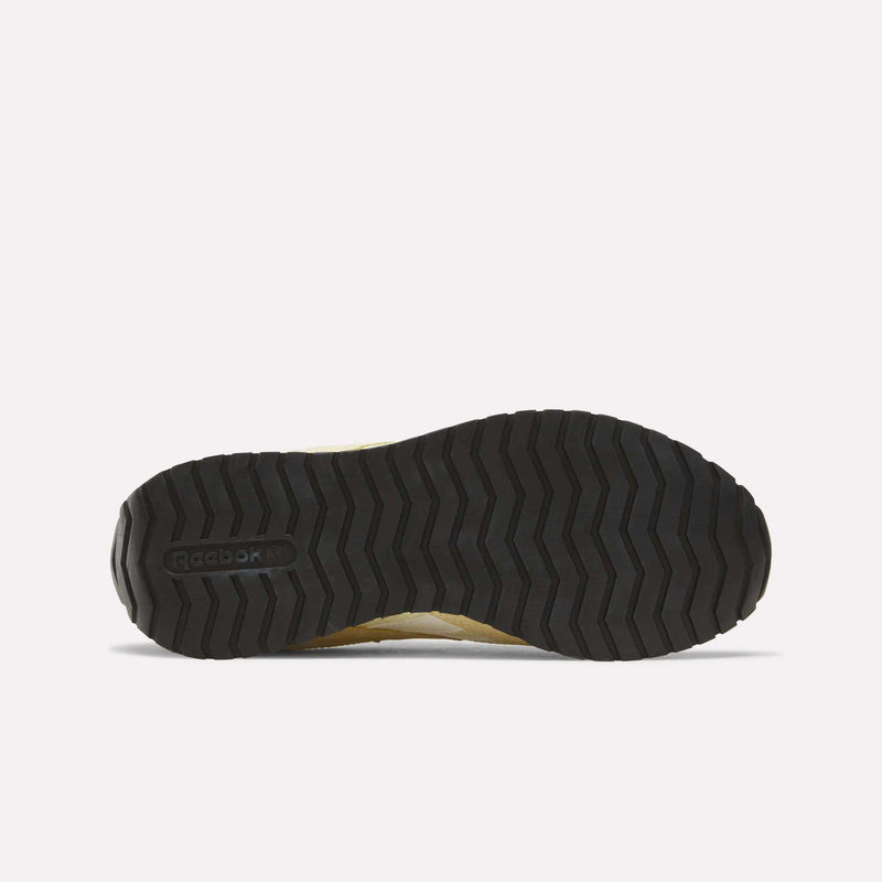 The image displays the bottom view of the Reebok Women’s Classic AZ Shoes, featuring a black rubber sole with a zigzag tread pattern and the Reebok logo embossed on the left side. The shoe’s design incorporates a crochet textile upper, seamlessly blending style and functionality to create textured sneakers that are both fashionable and practical.