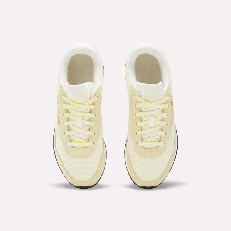 A pair of Women’s Classic AZ Shoes by Reebok in light yellow with white accents, shown from above, featuring a crochet textile upper and laces, black outsoles, and displayed on a plain white background.