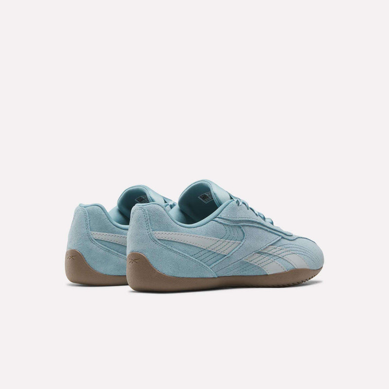 A pair of Women’s Ultra Lo Shoes by Reebok in light blue, showcasing a suede upper with white stripes on the sides and tan rubber soles, set against a plain white background.