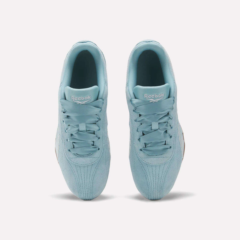 A pair of Reebok Women’s Ultra Lo Shoes in light blue are shown from above on a white background, highlighting their symmetrical laces, Reebok branding on the tongues, and a premium suede upper for a sleek, motorsport-inspired look.