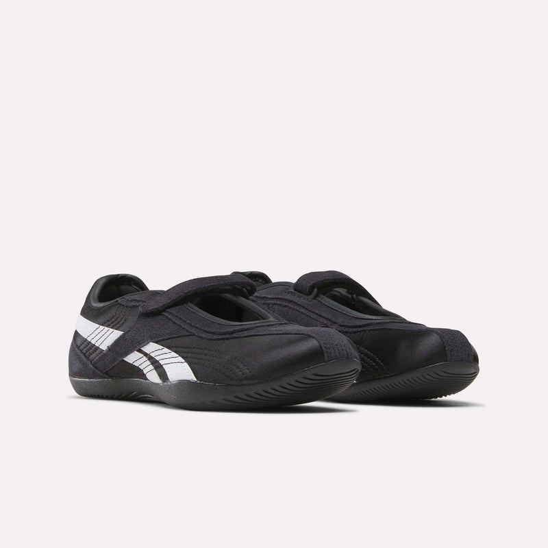 A pair of Women's Ultra Lo Mary Jane Shoes by Reebok, black with white stripes and Velcro straps, styled as low-profile runners and displayed side by side on a plain white background.