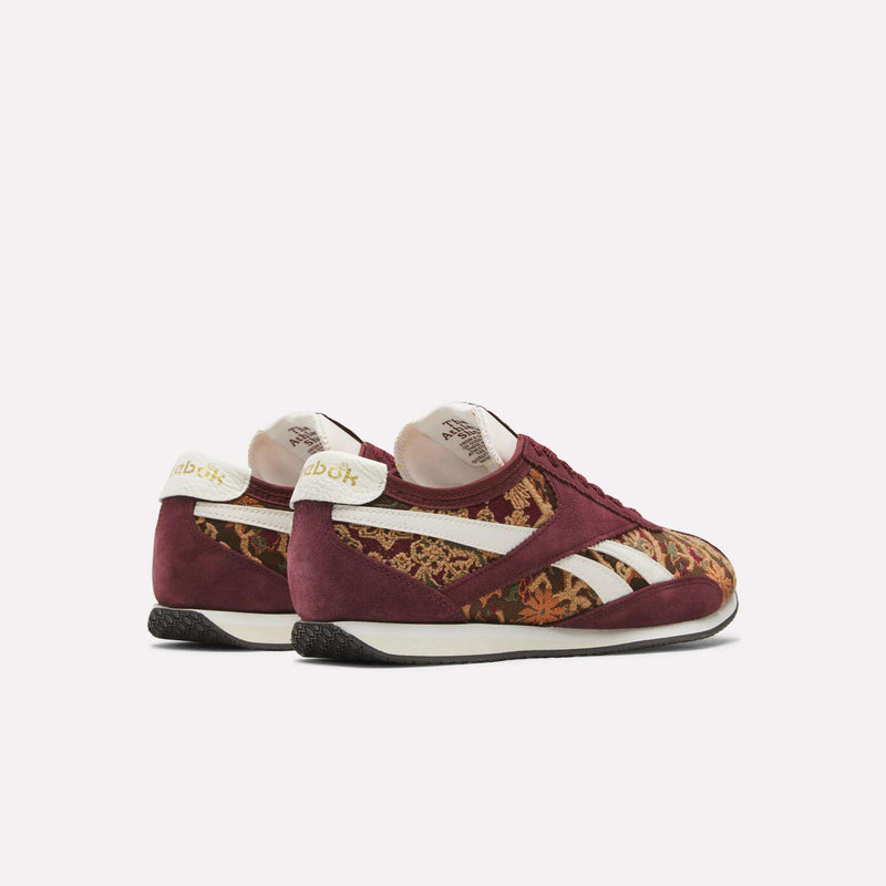 A pair of Reebok R400 Shoes featuring maroon suede uppers, white accents, and gold floral patterns on the sides and toe, displayed from back and side angles against a light background. These sneakers combine classic heritage design with modern detailing for a striking appearance.