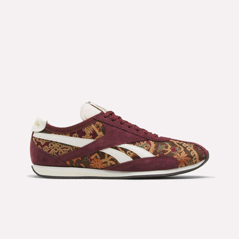 A maroon Reebok R400 shoe featuring white stripes and a floral brocade pattern along the sides, complete with maroon laces and a white sole, is displayed on a simple light background—this heritage-inspired design highlights the enduring appeal of Reebok’s premium R400 Shoes.