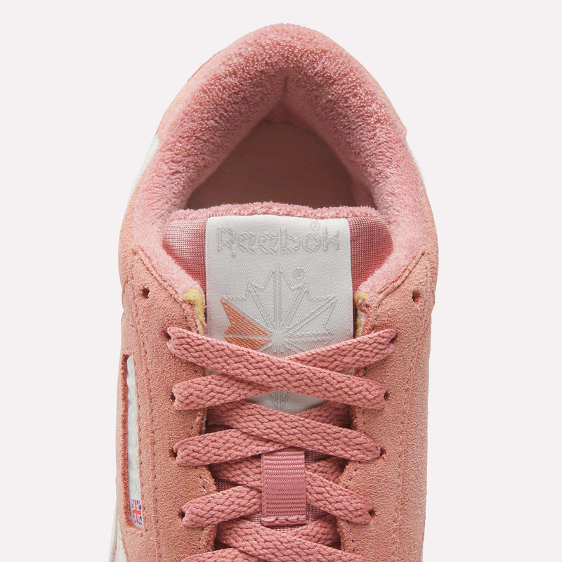 Close-up top view of Reebok Women's Freestyle Lo Shoes in pink suede, featuring pink laces, a white tongue with the Reebok logo, and a soft inner lining—showcasing classic retro sneaker details.