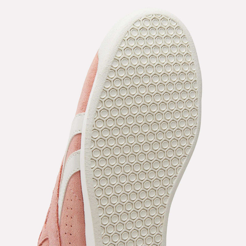 Close-up of the sole of the pink Reebok Women's Freestyle Lo Shoes, featuring a white hexagonal-patterned bottom and a white side stripe for a stylish retro look.