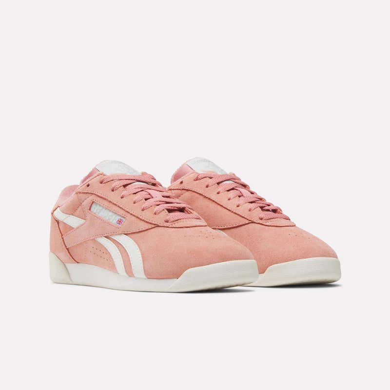 The Women's Freestyle Lo Shoes by Reebok feature pink suede, white accents and laces, retro design, and white rubber soles. These sneakers are displayed on a plain white background.