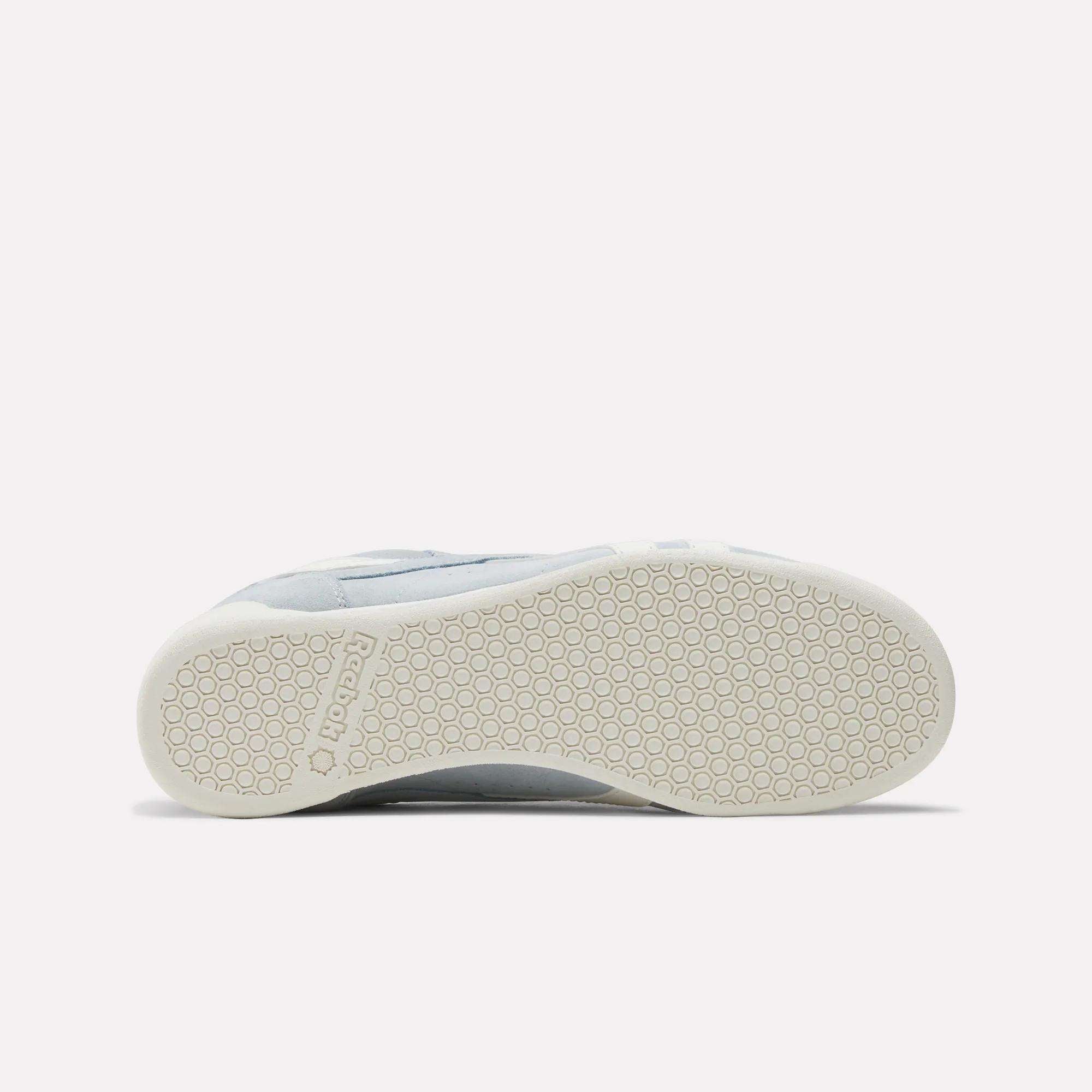 The Reebok Women's Freestyle Lo Shoes feature a white, hexagonal-patterned sole shown from the bottom on a plain background—ideal for fans of retro sneakers.