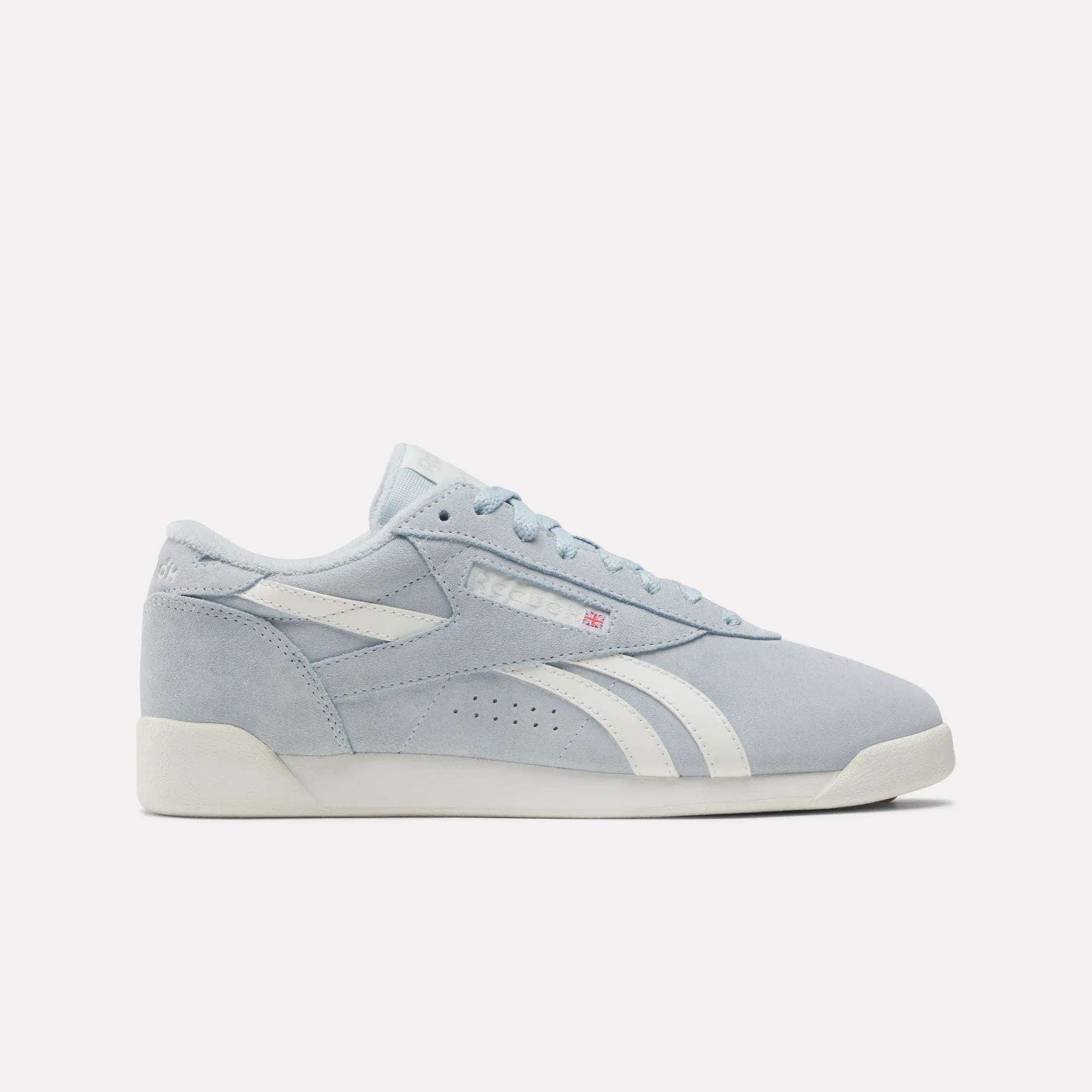 The Women's Freestyle Lo Shoes by Reebok feature a light blue retro design with suede accents, a white sole, and the Reebok logo on the side, shown against a plain white background.
