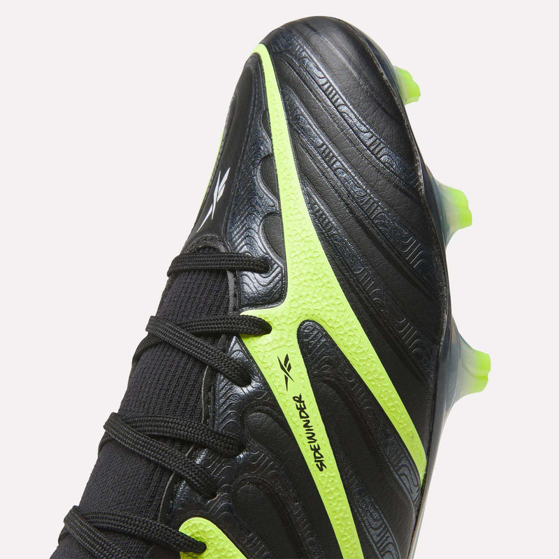 Close-up of black Reebok Sidewinder 26 Elite FG Cleats with textured patterns for ball control, neon yellow-green accents, and black laces. “SPEED HUNTER” appears on a yellow-green strip—ideal for firm grass surfaces.