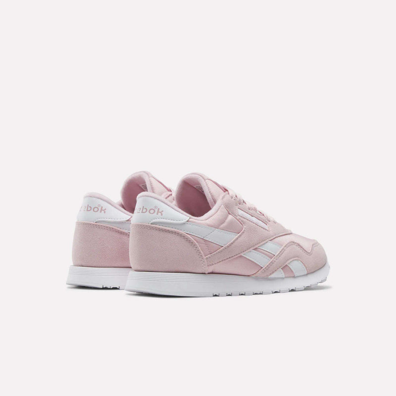 A pair of Reebok Women's Classic Nylon Shoes in light pink, featuring white accents and white soles, displayed at an angle on a plain white background.