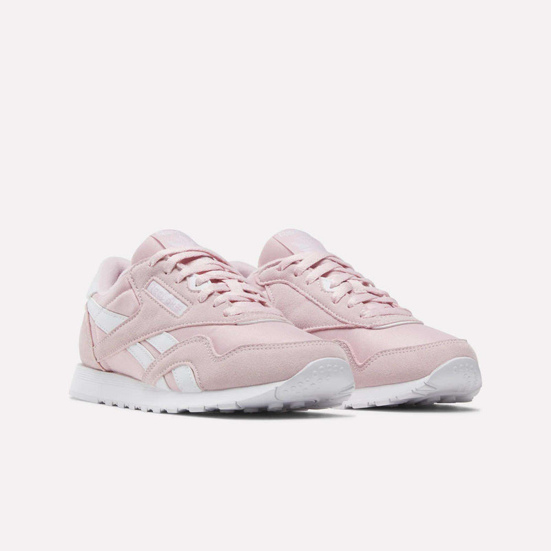 A pair of Women's Classic Nylon Shoes by Reebok in light pink, featuring white soles and white Reebok logo accents, displayed on a plain white background.