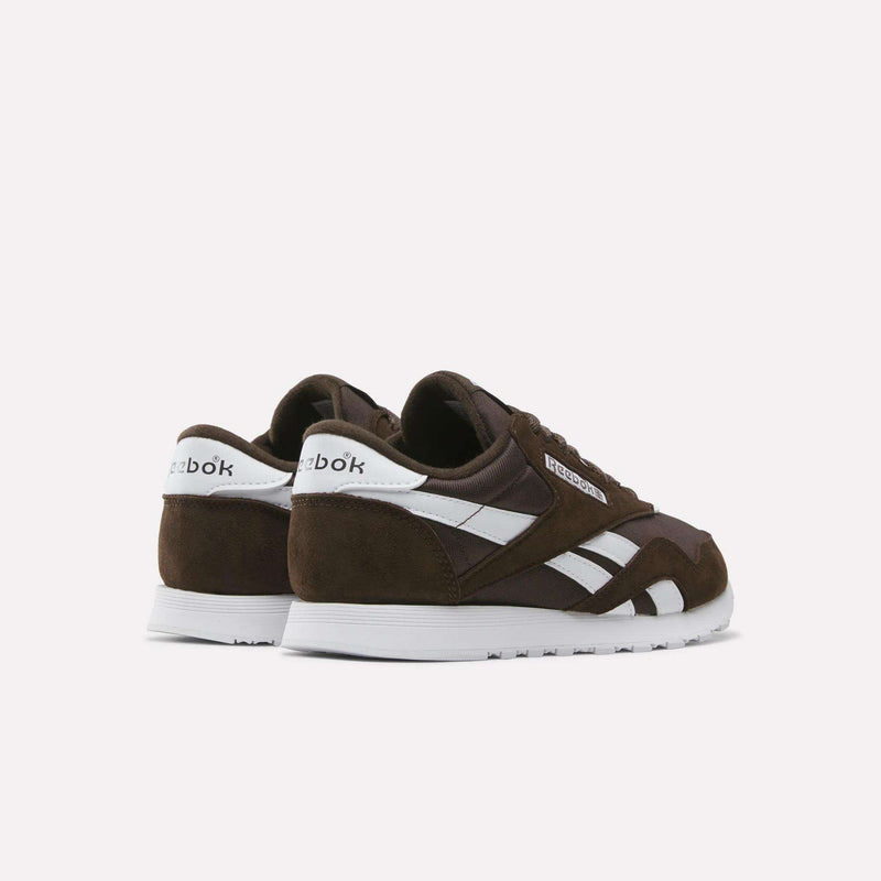A pair of Reebok Women’s Classic Nylon Shoes in brown, featuring white soles and signature white side stripes, are displayed against a plain white background, showcasing a timeless vintage style ideal for enthusiasts of iconic women’s sneakers.