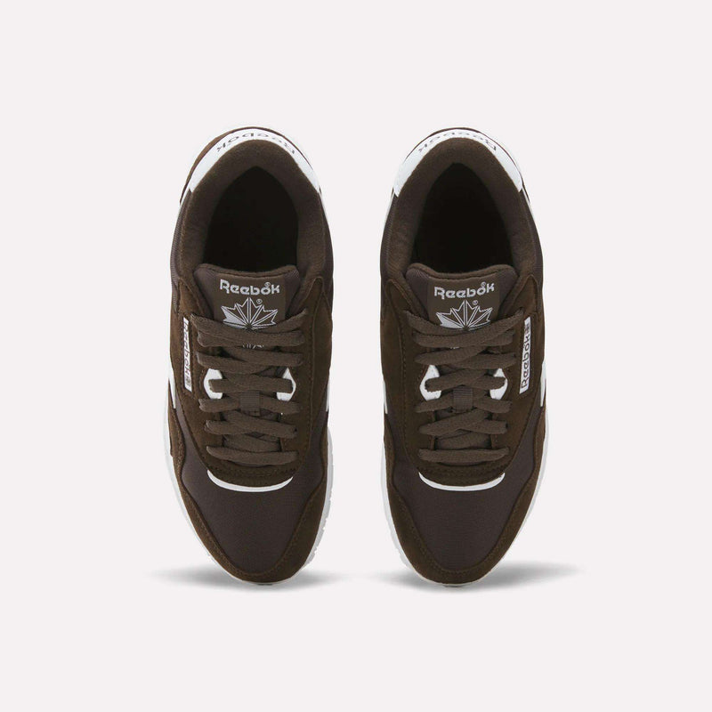 Top view of a pair of Reebok Women’s Classic Nylon Shoes in dark brown with white detailing, featuring white soles and Reebok logos on the tongues and sides, arranged side by side on a white background for a subtle vintage look.