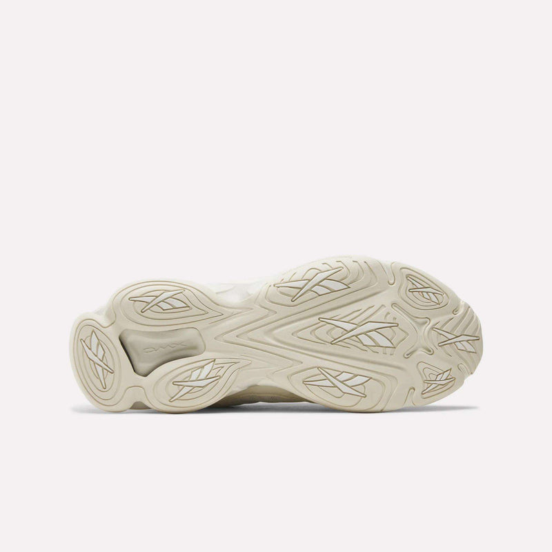 The image displays the outsole of Reebok's DMX Series 3000 Shoes facing up, in light beige with wavy and geometric tread patterns for grip. The intricate design emphasizes comfort, with visible adiPRENE branding on one section.