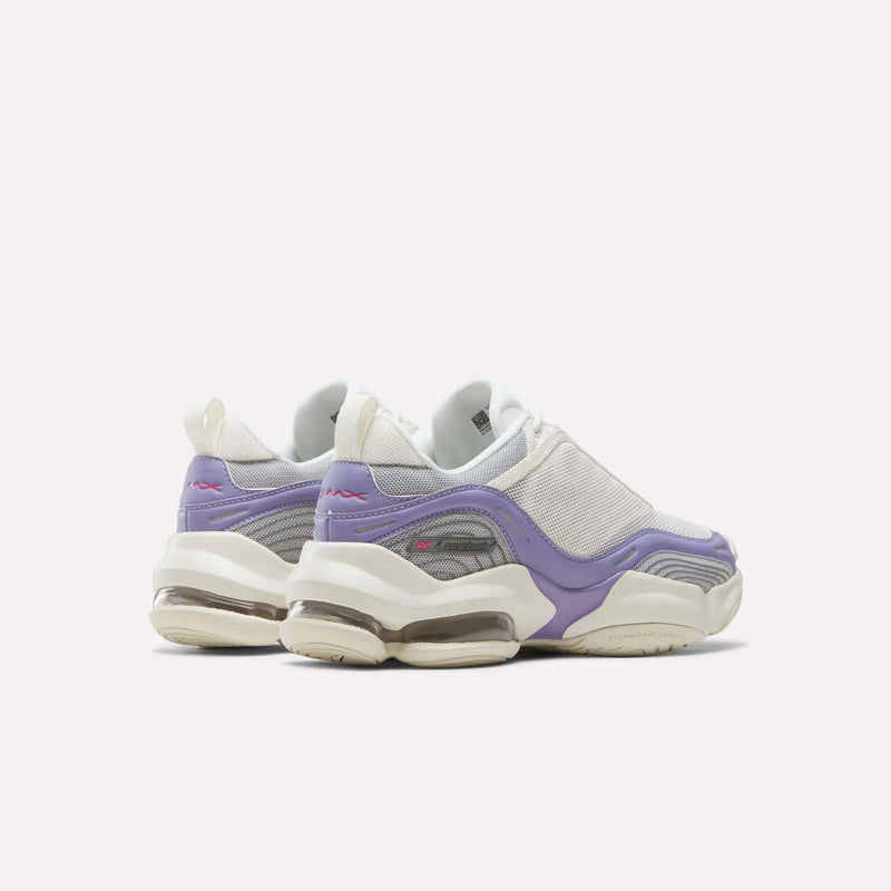 A pair of Reebok Women’s DMX Series 3000 Shoes in white and purple, designed with mesh panels, chunky soles, and visible air cushioning that incorporates DMX moving air technology for lightweight support, shown positioned facing away from the camera on a plain white background.